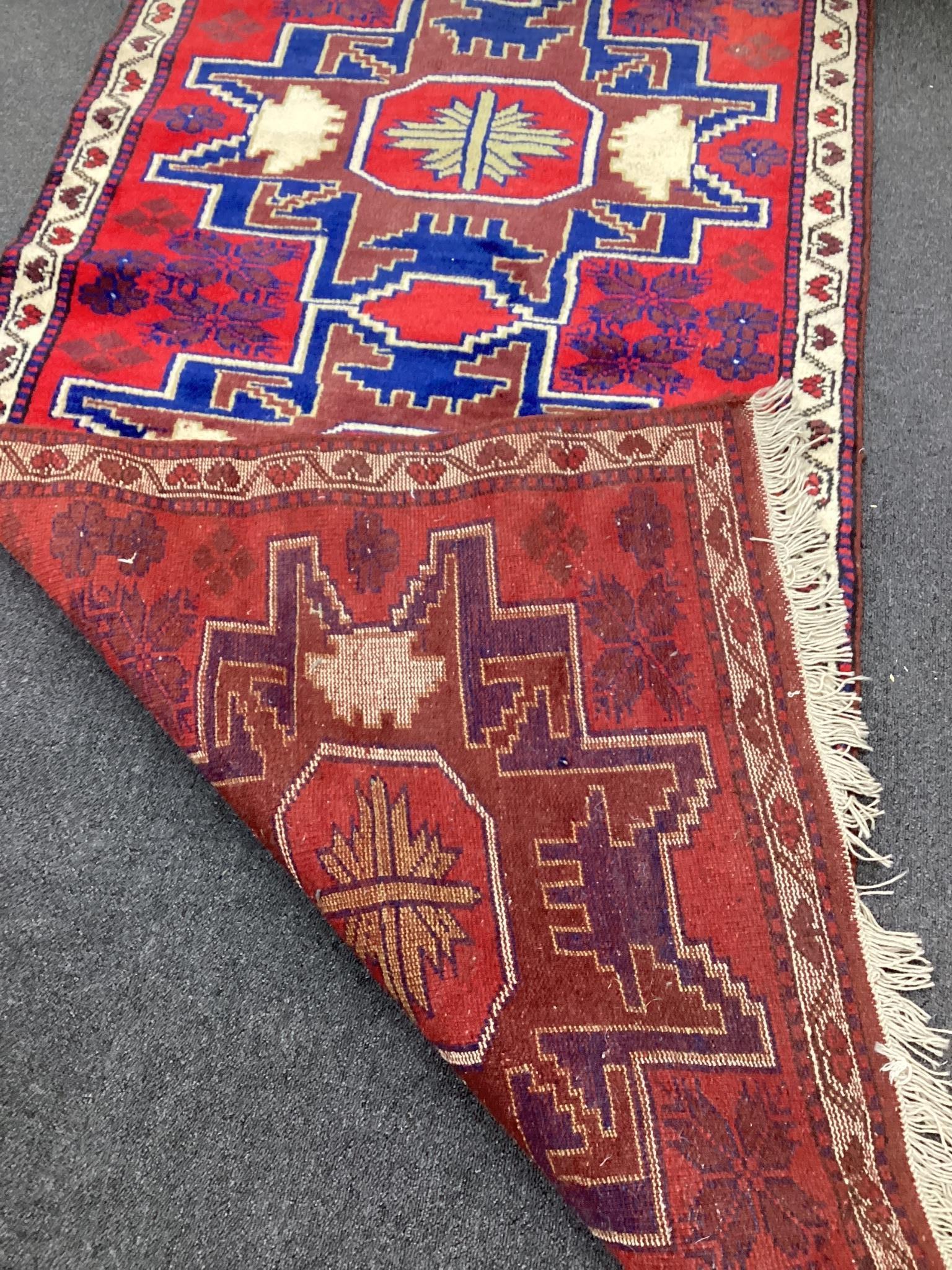 A Caucasian style red ground triple medallion rug, 180 x 98cm